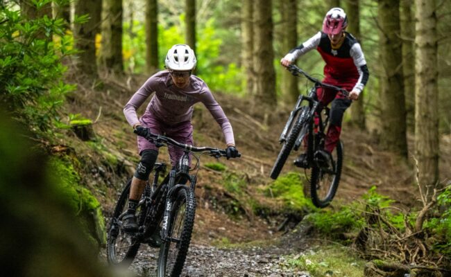Two mountain bike riders on a technical singletrack forest trail