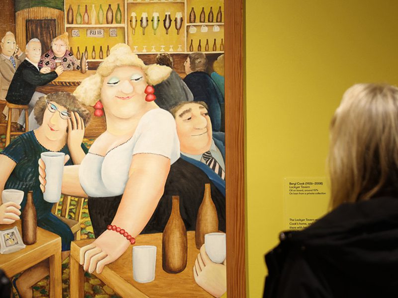 A visitor looks at a Beryl Cook painting