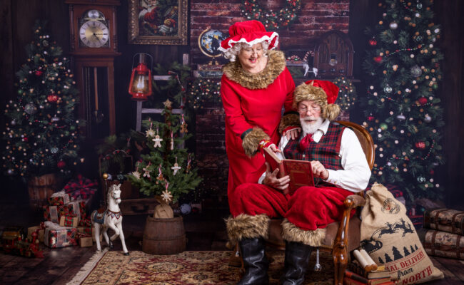 Father and Mother Christmas sat in front of a fireplace with toys