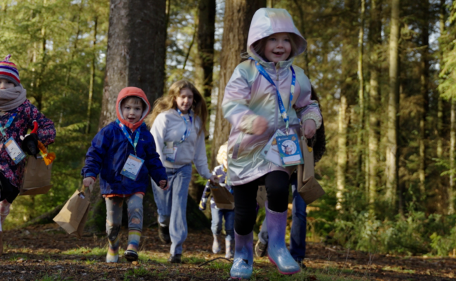Children in winter coats running along a forest road