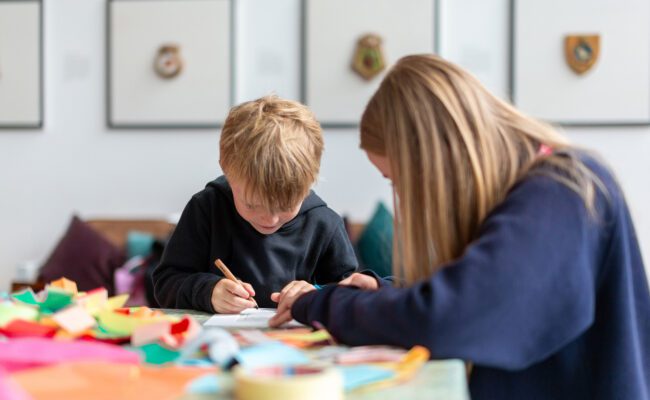 A woman and a young boy sit at a table colouring at The Box Plymouth