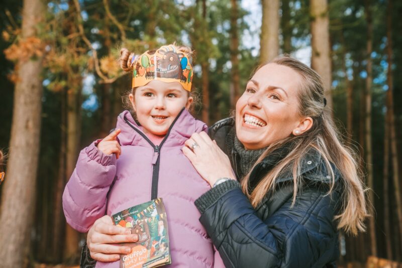 A woman is holding a child wearing a paper crown