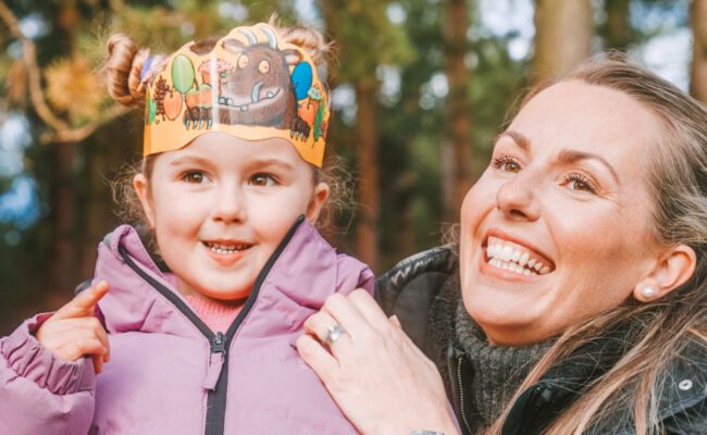 A woman is holding a child wearing a paper crown