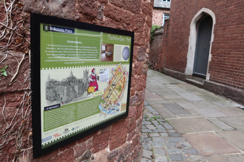 Woollen Trail panel on the side of St Nicholas Priory