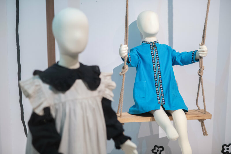 Two items of childrens clothing displayed on mannequins, one on a swing.
