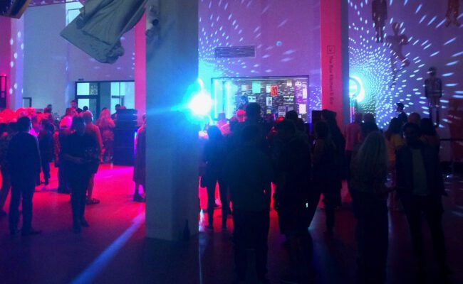 Photograph showing a busy space lit up at night with people dancing
