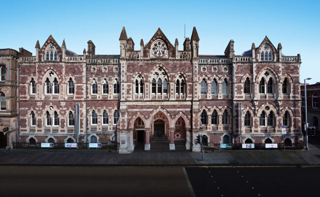 the exterior of a Victorian gothic museum, with a blue sky above