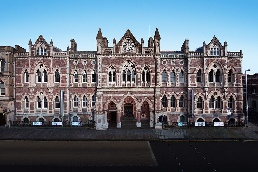 the exterior of a Victorian gothic museum, with a blue sky above