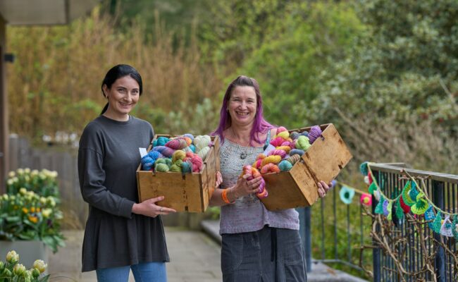 Women hold crates of colourful wool at RHS Rosemoor