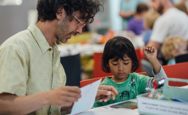 A father and daughter taking part in a craft activity.