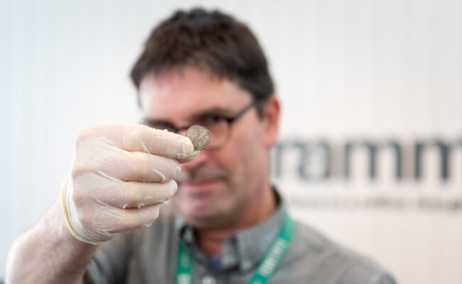 a man holding a small silver penny up to the camera