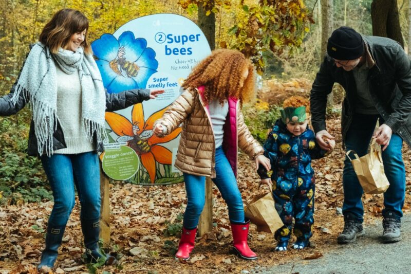 A family plays in front of a Superworm trail sign