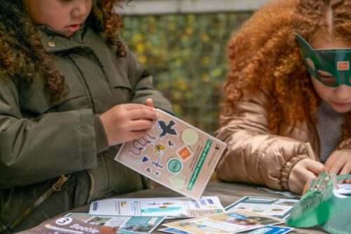 Two children play with activity sheets and stickers