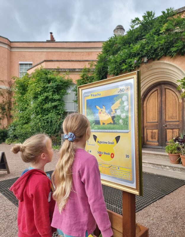 Two children looking at a Pikachu artwork outside the house at Killerton.
