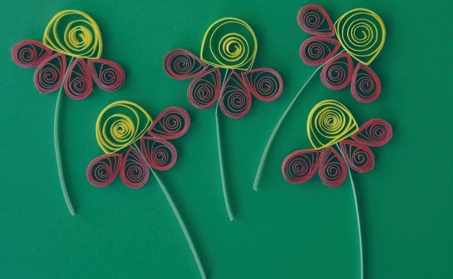 paper quilling flowers on top of a dark green background