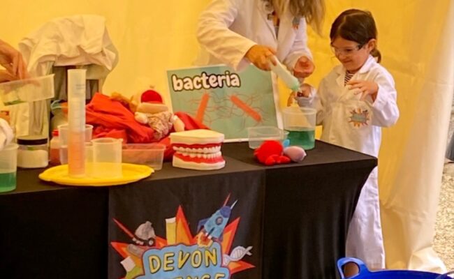 a woman and child in white lab coats doing a science experiment