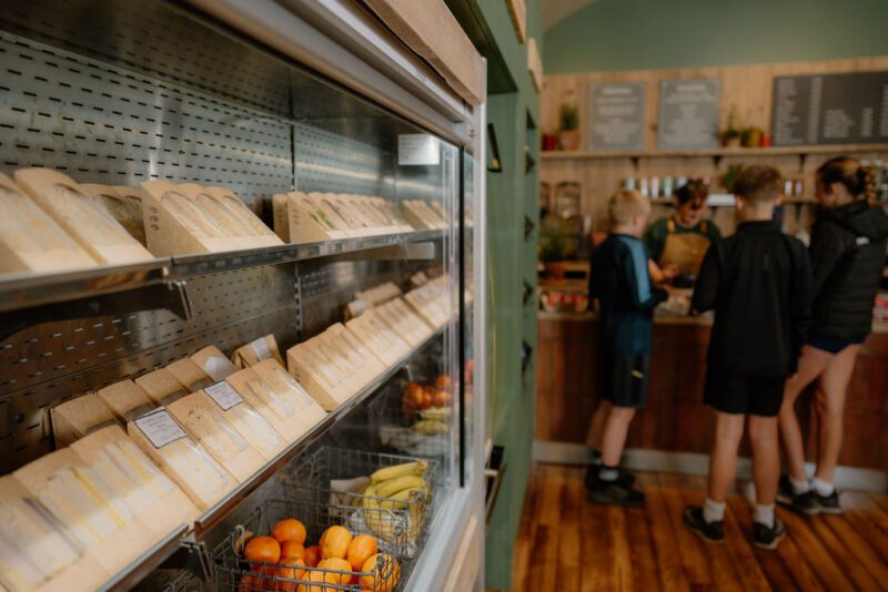 A group of children being served in The Pantry takeaway with the refrigerated sandwich display in the foreground