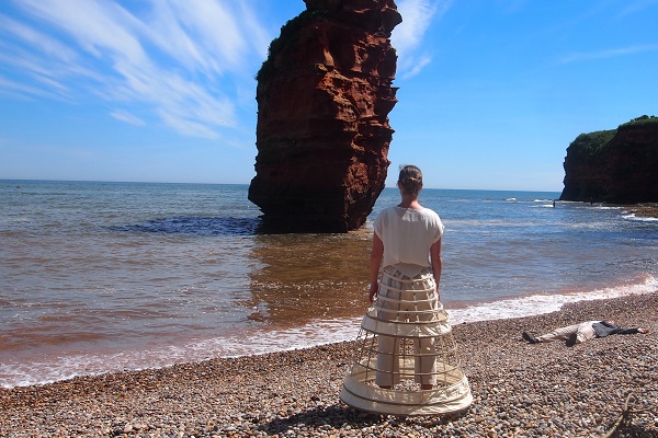 Woman stood on the coast facing the sea, from the film 'Calling of the Tide'