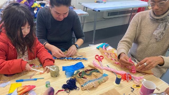 two women and a girl sitting at a table doing textile arts